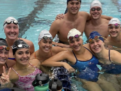 men's and women's swimmers in a pool looking happy